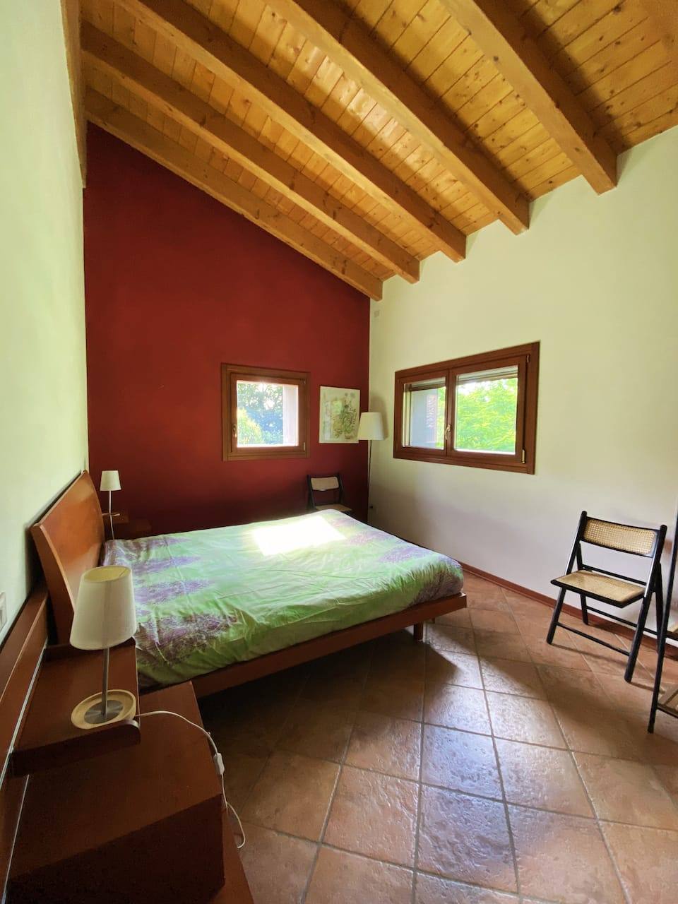 Bedroom with dark-red accent wall and beamed ceiling